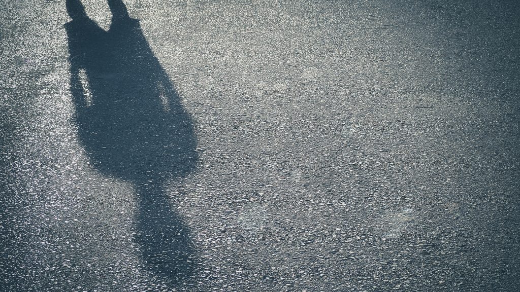 Skugga av en person faller mot asfalt