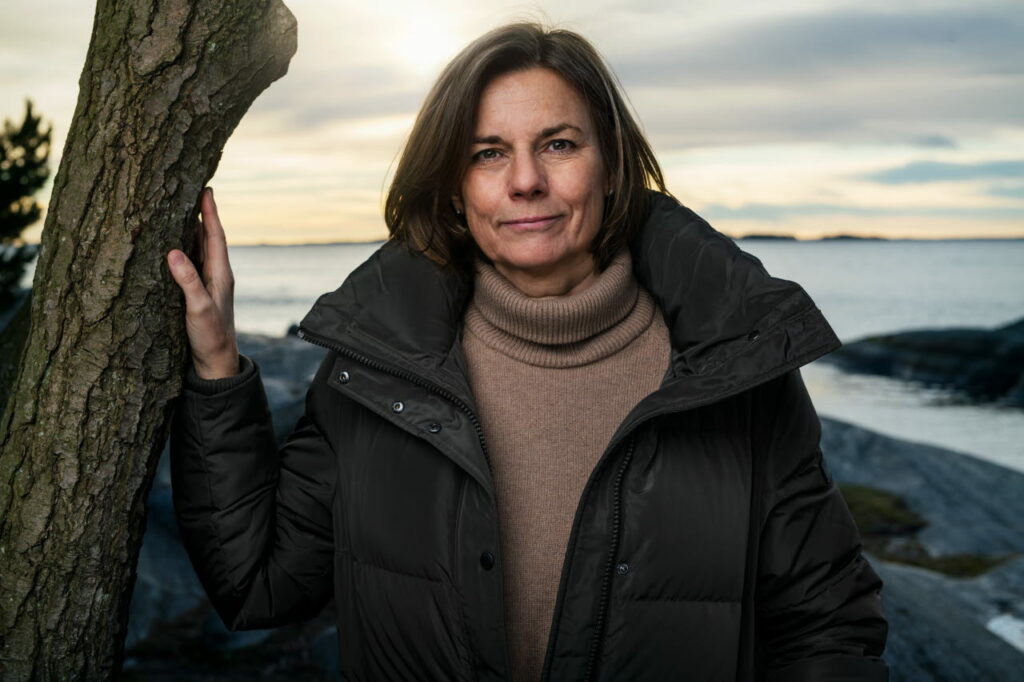 Foto av Isabella Lövin vid ett träd med ett hav i bakgrunden.